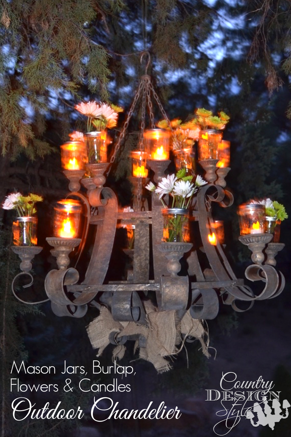 Outdoor chandelier lit up at night. Mason jars hold battery candles and cut flowers. Burlap is rustic and shabby along the bottom. Fun for our family gatherings. Country Design Style www.countrydesignstyle.com