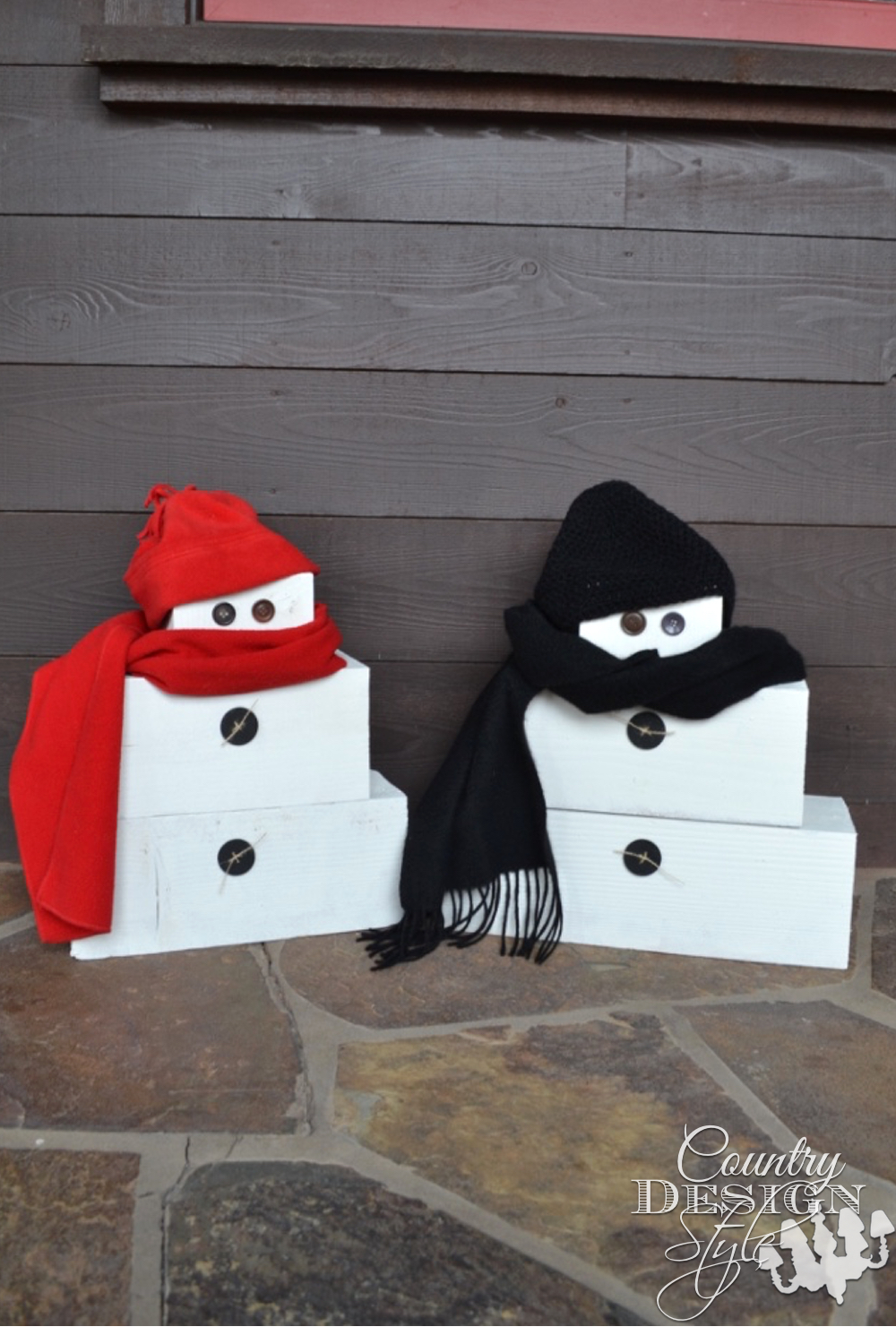 Scrap pile wood from construction site is turned into a couple of snow people. Button eyes, scarves and knit caps. | countrydesignstyle.com