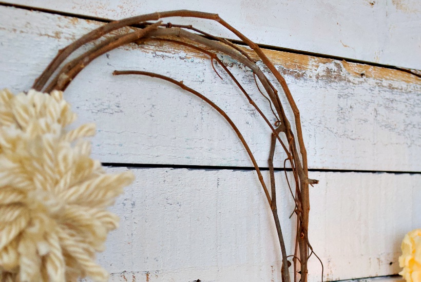 Winter grapevine wreath with pom pom on rustic white paint wood wall.