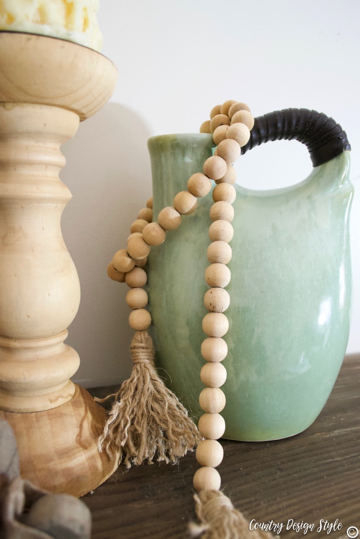Green vase with wood beaded garland and wood candleholder