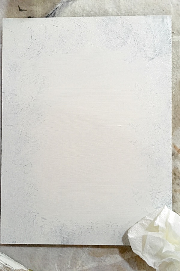 white painted board with some of the paint removed around the edges to reveal brown paint.