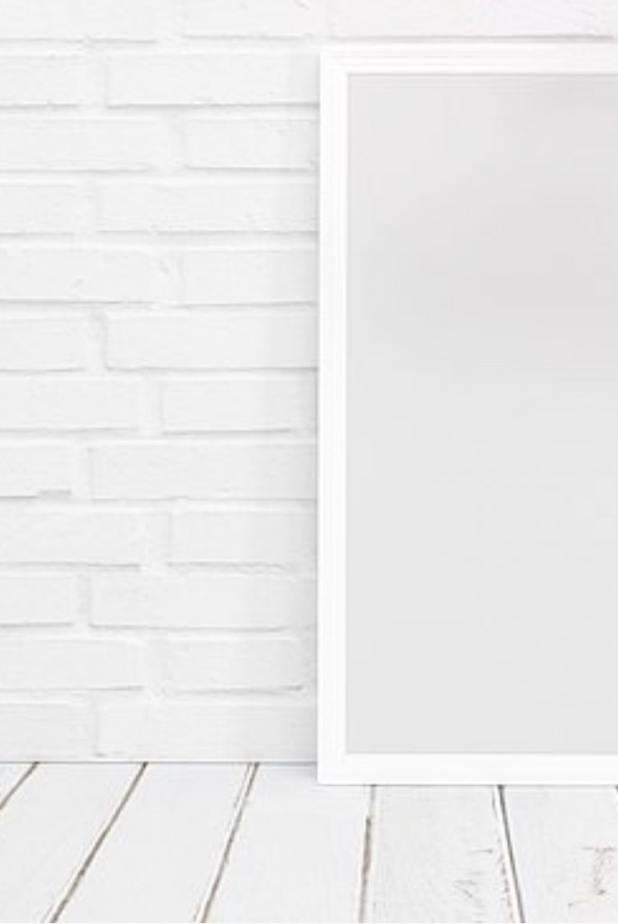white brick wall with white empty frame and wood table top