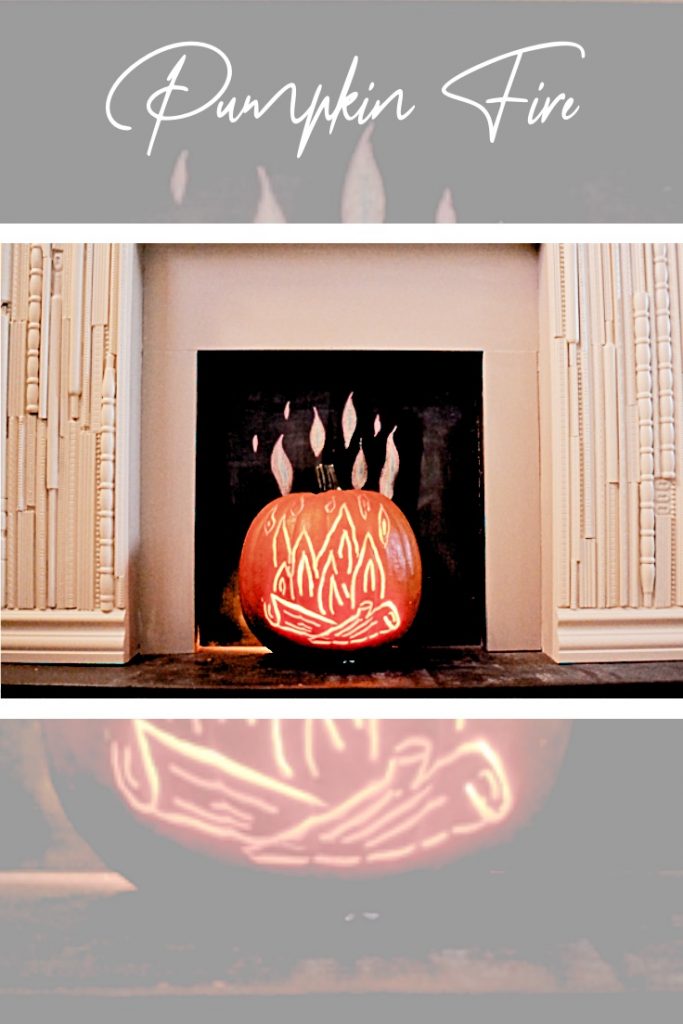 orange pumpkin with fire carved and sitting in fake fireplace.