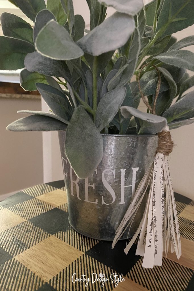 Tassel hanging from the metal pot with faux green plants